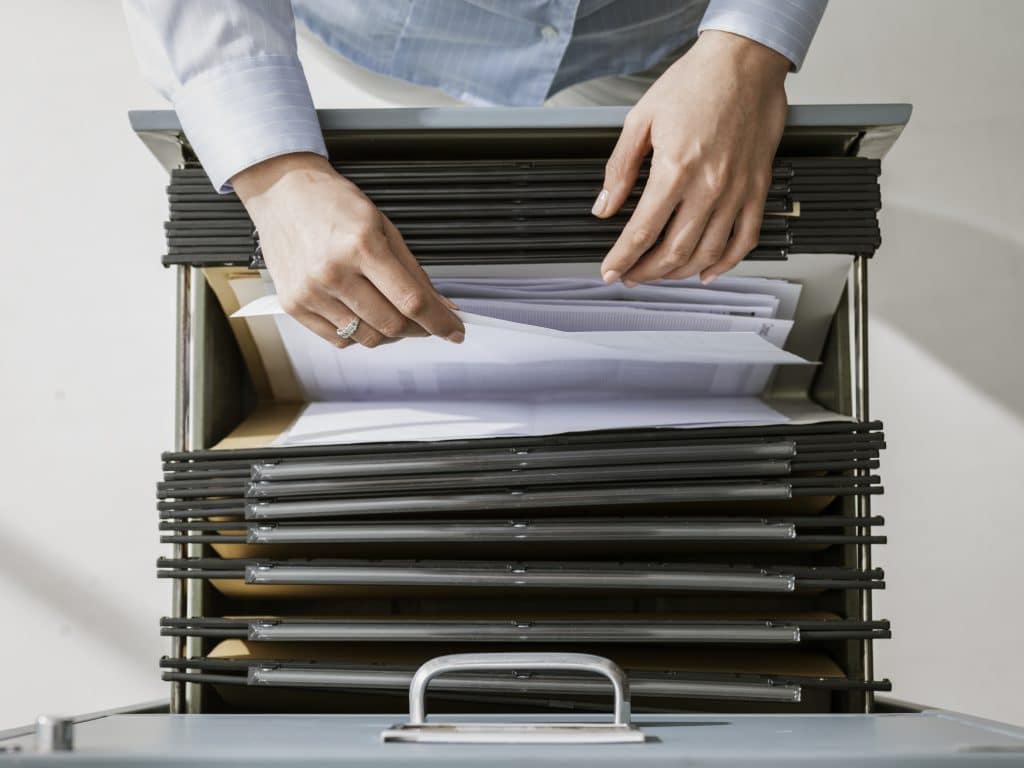 hands putting paper into file drawer